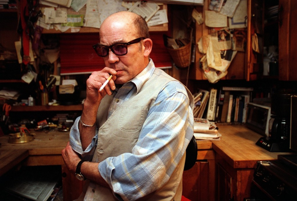 Hunter S. Thompson with a cigarette in front of his desk.