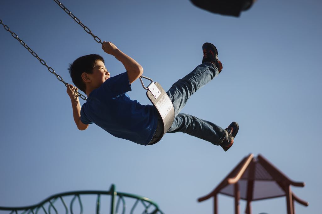 Kid swings high on a playground swing